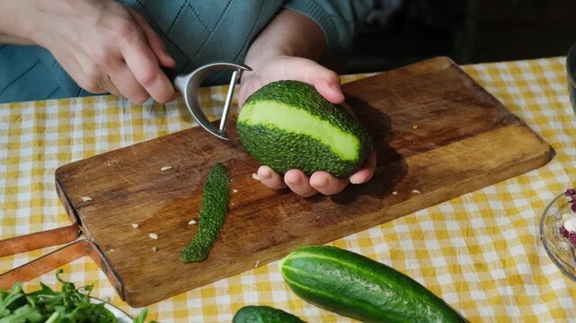 Food prep. Woman peeling avocado for making summer diet salad