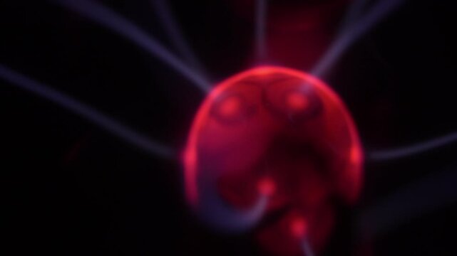 Close-up of a plasma ball coil that creates red and white energy beams.