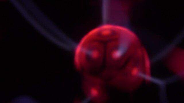 Close-up of a plasma ball coil that creates red and white energy beams.