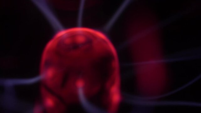 Close-up of a plasma ball coil that creates red and white energy beams.