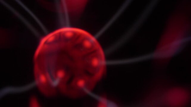 Close-up of a plasma ball coil that creates red and white energy beams.