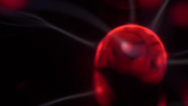 Close-up of a plasma ball coil that creates red and white energy beams.