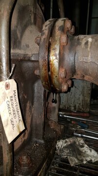 Corroded flange seeping oil with maintenance required tag for wind turbine pump inspection background