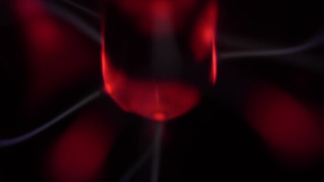 Close-up of a plasma ball coil that creates red and white energy beams.