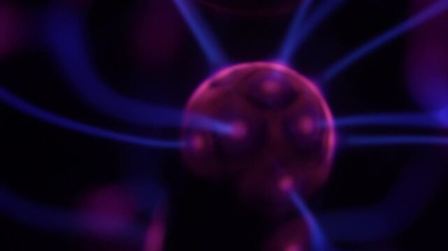 A close-up of a plasma ball coil that creates energy beams in shades of purple.