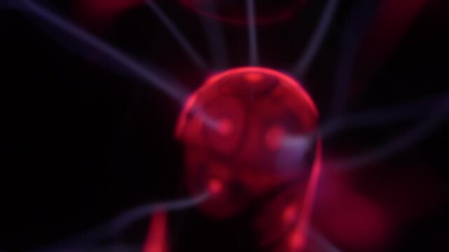 Close-up of a plasma ball coil that creates red and white energy beams.