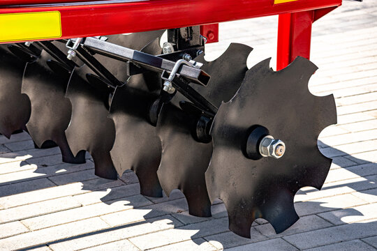 Agricultural disc harrow notched blades for soil cultivation. Modern farm machine tillage equipment unit component closeup view with steel axle and industrial technical details for tractor.
