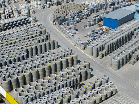 Aerial view of a large industrial yard filled with stacks of cylindrical concrete pipes and precast elements arranged in rows in Krakow, Lesser Poland Voivode, Poland.