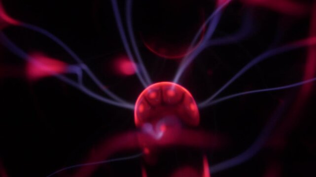 Close-up of a plasma ball coil. The plasma ball creates beams of energy in red and purple.