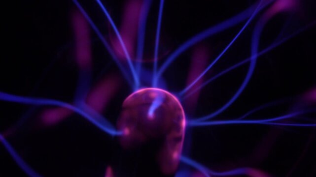 Close-up of a plasma ball coil. The plasma ball creates purple energy beams.
