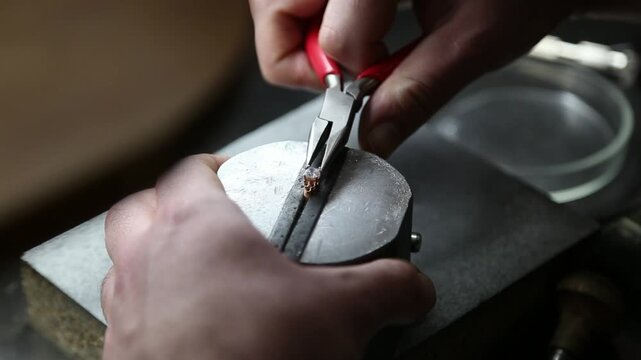 A jeweler sets a gemstone into a ring. Engagement ring. Golden ring with a diamond. Jewelry manufacturing