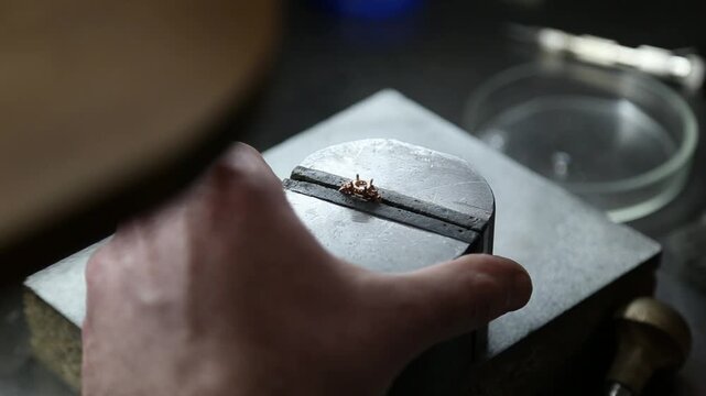 A jeweler sets a gemstone into a ring. Engagement ring. Golden ring with a diamond. Jewelry manufacturing