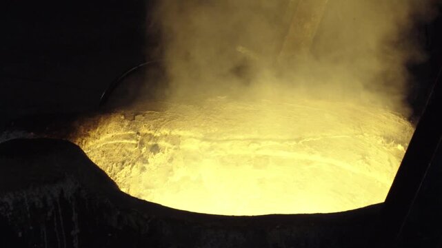 Molten metal glowing brightly in a heavy industrial foundry ladle