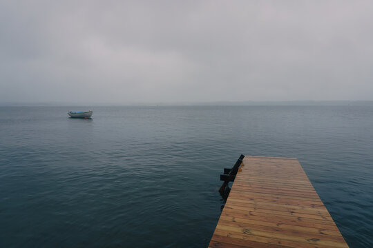 Wooden pier and boat on foggy lake