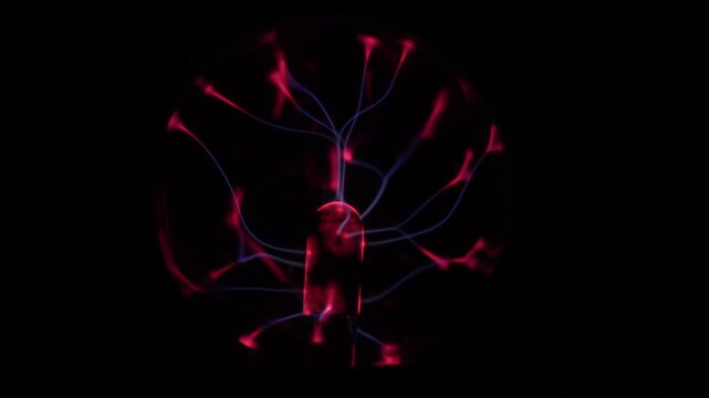 Close-up of a working plasma ball. The plasma ball's coil creates red and violet electric rays.
