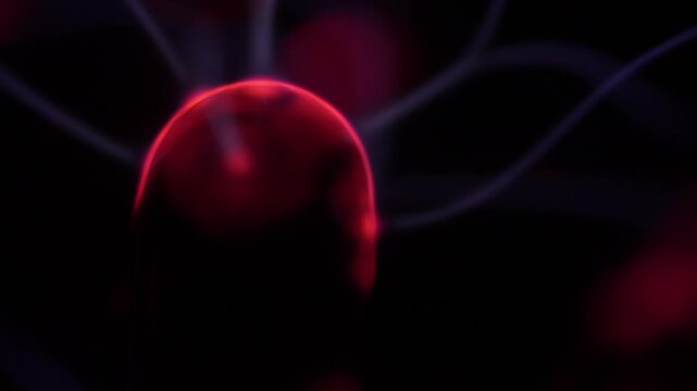 Close-up of the plasma ball coil during operation. The plasma ball generates red and white rays.