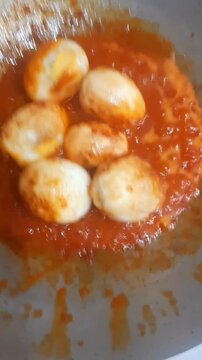 Frying Eggs for Balado Chili Sauce. The eggs are cooked in hot oil before being combined with a spicy red chili sauce made from chilies, tomatoes, onions, and aromatic spices.