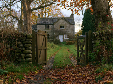 Rural cottage viewed through gate in autumn landscape