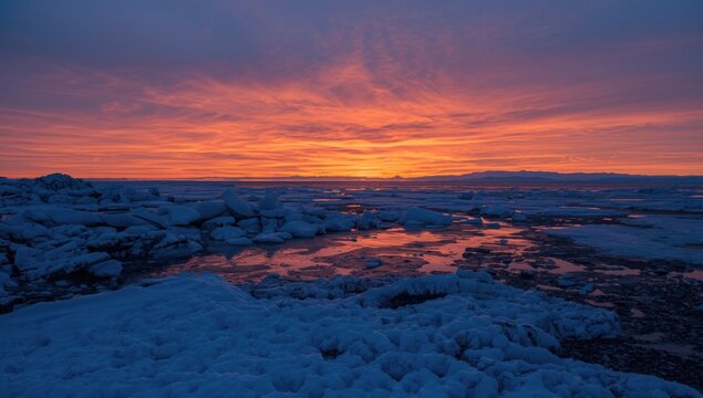 Vibrant Sunset Over Icy Landscape with Reflections in Cold Colors