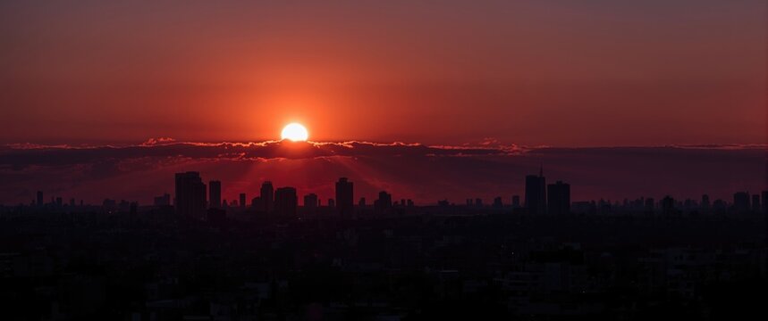 Sunset Over a City Skyline with Silhouetted Buildings and Warm Colors