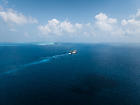 Aerial view of a cargo ship sailing through the deep blue waters of the Indian Ocean near Dhidhdhoo, Thiladhunmathee Uthur, Maldives.