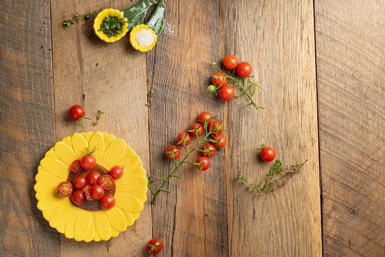 Ripe, red, cherry tomatoes with fresh thyme and sea salt on a sunflower dish plate.