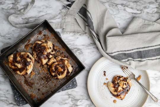 Small batch chocolate cinnamon buns, knots, or twist freshly baked, with a marble background.