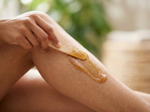 Closeup of a womans leg receiving a waxing hair removal treatment with warm sugar wax.