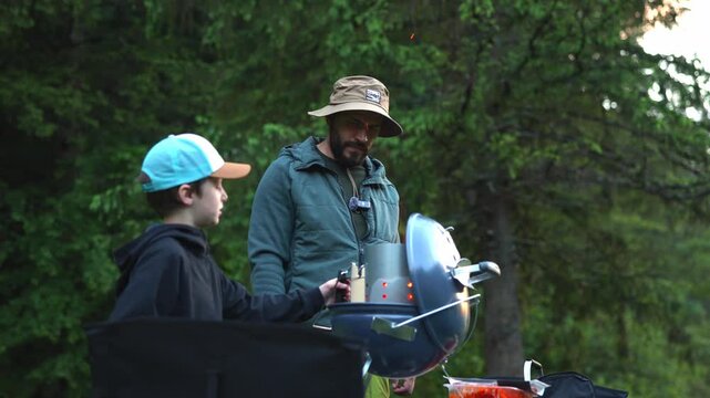 Father and son preparing a barbecue grill during camping trip