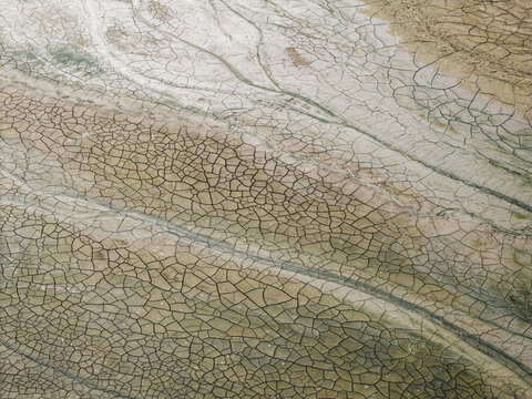 Aerial view of cracked dry earth patterns on a mudflat with intricate fissures and parched soil textures in Krynica Morska, Pomeranian Voivodeship, Poland.