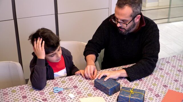 Boy and father packing Christmas presents together