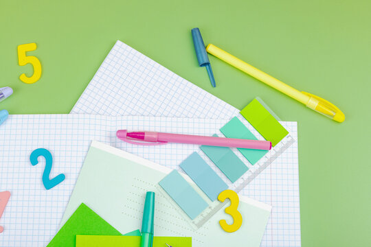 Back-to-school concept, flat lay composition of school supplies on a green background