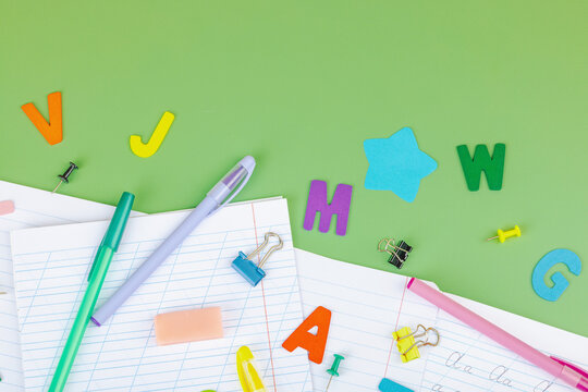 Back-to-school concept, flat lay composition of school supplies on a green background