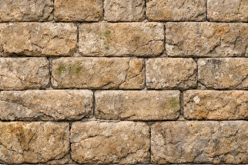 Fototapeta premium A high resolution full frame background image featuring a textured surface of rustic brown stone blocks arranged in a traditional horizontal brick wall pattern design