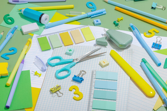 Back-to-school concept, flat lay composition of school supplies on a green background