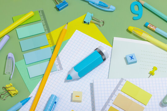 Back-to-school concept, flat lay composition of school supplies on a green background