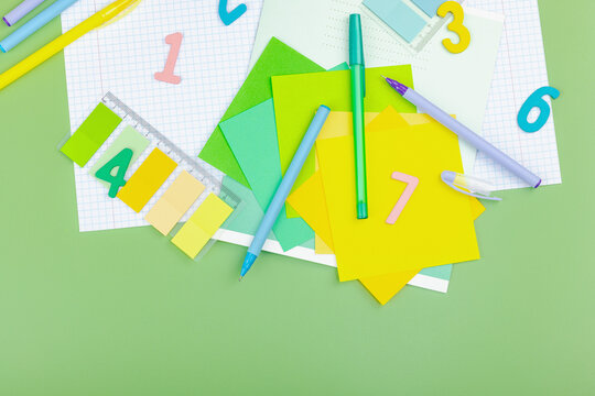 Back-to-school concept, flat lay composition of school supplies on a green background