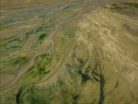 Aerial view of the tidal flats and intricate water channels of the Vistula Spit, featuring green algae and sandy textures in Krynica Morska, Pomeranian Voivodeship, Poland.
