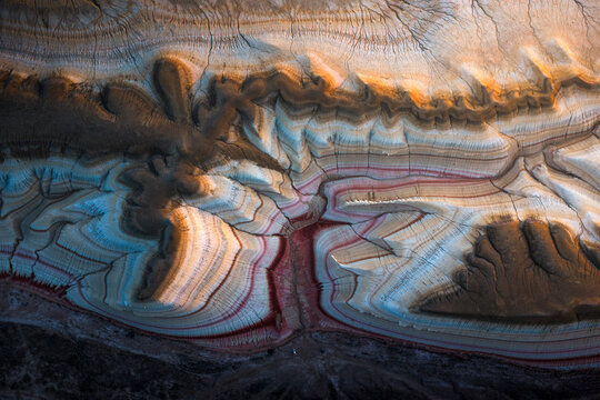 Aerial view of the colorful sedimentary rock formations of Kyzyl Kup, with layered stripes of red, white, and blue clay in Karakiya District, Mangystau Region, Kazakhstan.