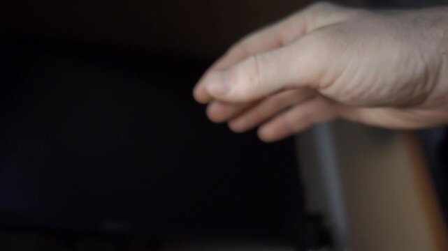 Close-Up of a Hand Reaching Towards a Computer Mouse in a Dark Room
