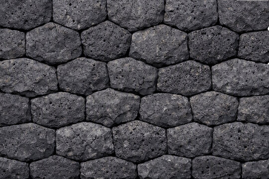 A detailed close up view of a dark grey stone pavement with a repeating hexagonal pattern creating an elegant and modern architectural texture background