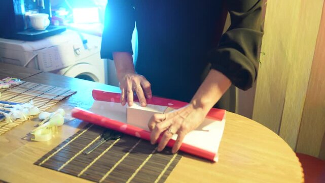 Woman Hands Wrapping a Birthday or Valentine Gift Box with Red Heart Pattern Paper