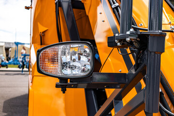 Yellow telehandler cabin exterior with front headlight unit. Modern construction machinery lighting assembly against sky background with heavy duty industrial transport vehicle details view. © NastyaPhoto