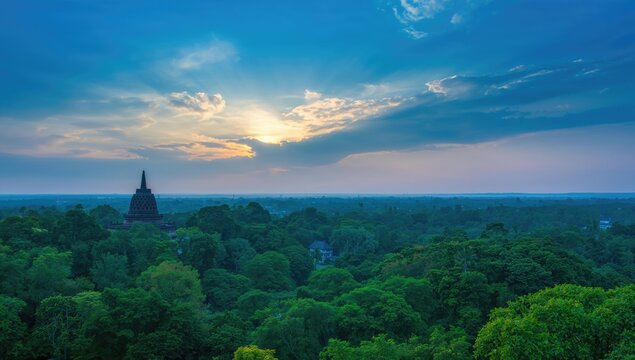 Buddhist Temple Silhouette Against Sunset Over Lush Green Landscape