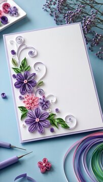 Handmade greeting card decorated with purple and pink paper quilling flowers. Floral filigree craft and creative hobby concept