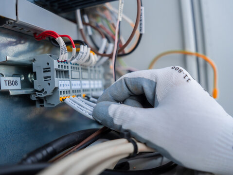 Close up of engineer hand checking the electrical system in control panel at industrial plant concept maintenance safety, service. Industrial manufacturing factory. Technician wiring circuit control 
