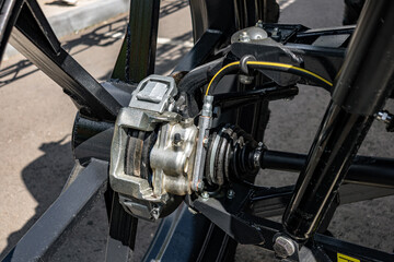 Fototapeta premium Disc brake caliper and CV joint on agricultural machine wheel hub. Close up detail of self propelled sprayer wheel assembly featuring brake rotor, caliper, axle drive shaft, and shock absorber.