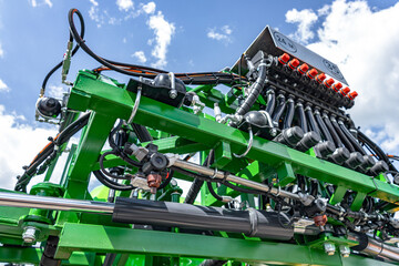 Section control valve manifold on agricultural boom sprayer. Field crop protection machinery detail featuring electric valve actuators with red caps, hydraulic hoses, and green metal frame. © NastyaPhoto