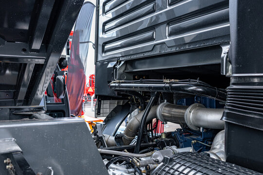 Semi truck tilted cabin back wall with engine exhaust pipes. Heavy commercial vehicle chassis mechanism frame section with silver corrugated bellows and industrial tractor transport details.