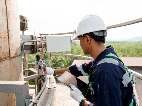 Energy engineer is using digital tablet to continues emission monitoring system, checking air pollution reduction in industrial plant or for Clean air eco friendly. Environment sustainable in factory 